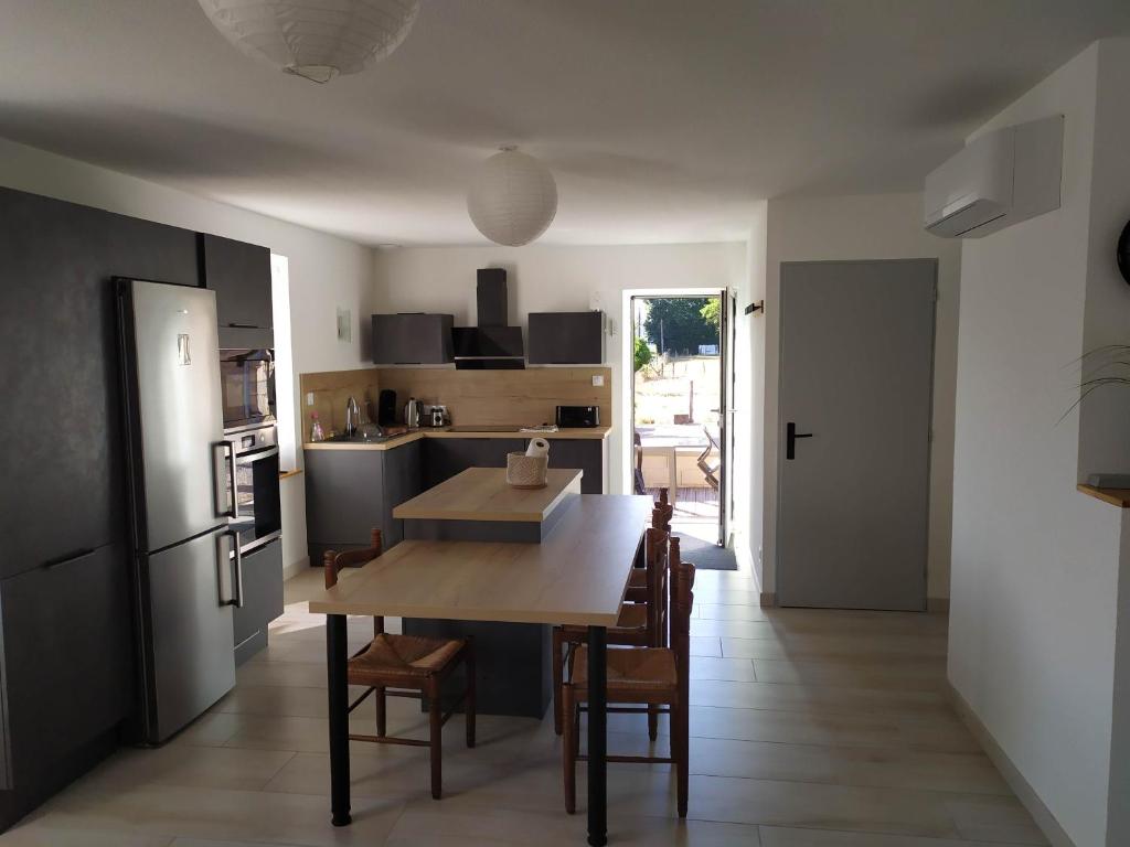 a kitchen and dining room with a table and a refrigerator at Meublé Climatisé 75 M2 in Souvans
