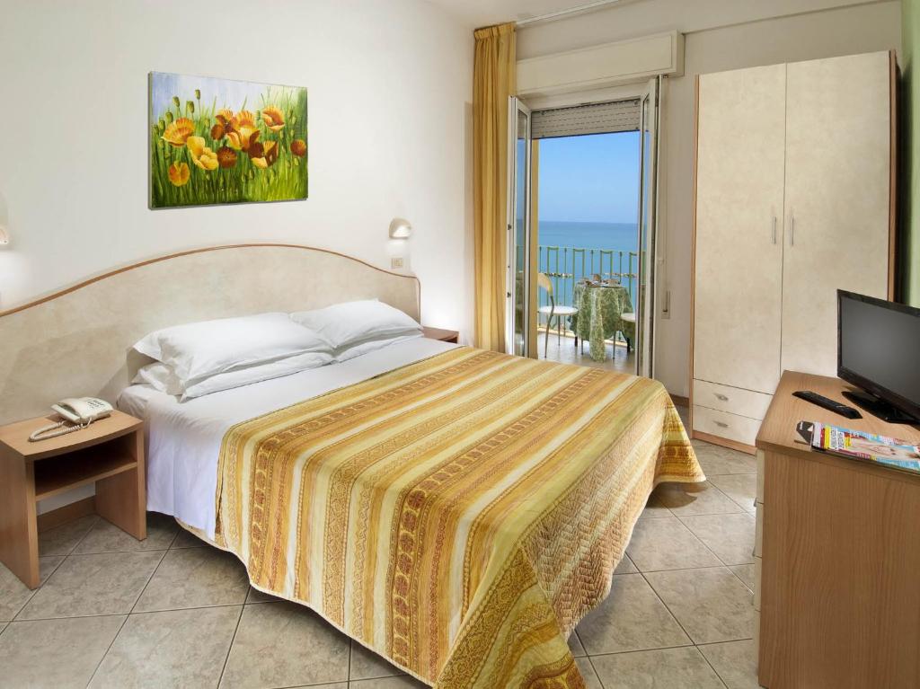 a bedroom with a bed and a television and a balcony at Hotel Gloria in Gabicce Mare