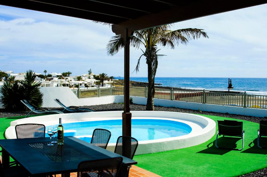 a swimming pool with a table and chairs and the ocean at Villa La Concha in Playa Honda