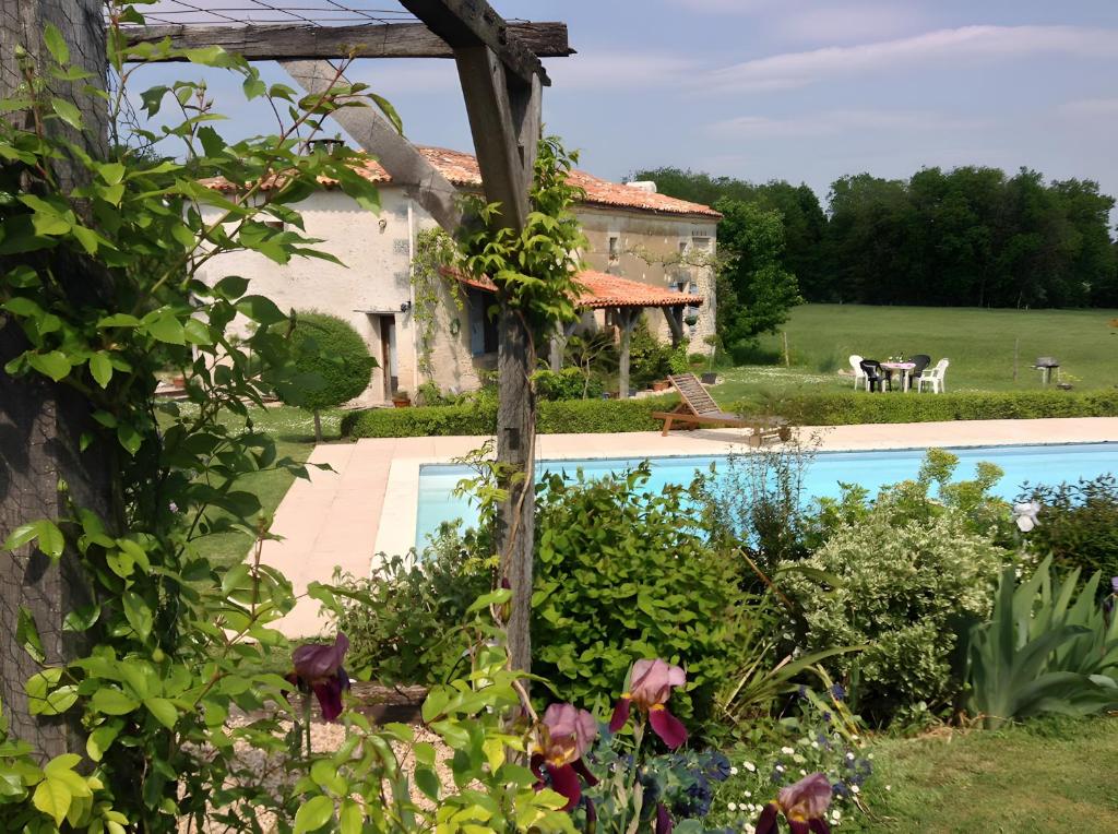 an external view of the house and the pool in the garden at Maison Les Fleuries in Saint-Quentin-de-Chalais