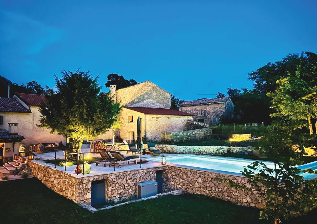 an estate with a swimming pool and a stone wall at Villa Olmeto in Lupoglav