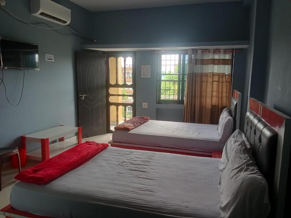 two beds sitting in a room with a window at Subhalaxmi Hotel and Lodge in Bahāsi