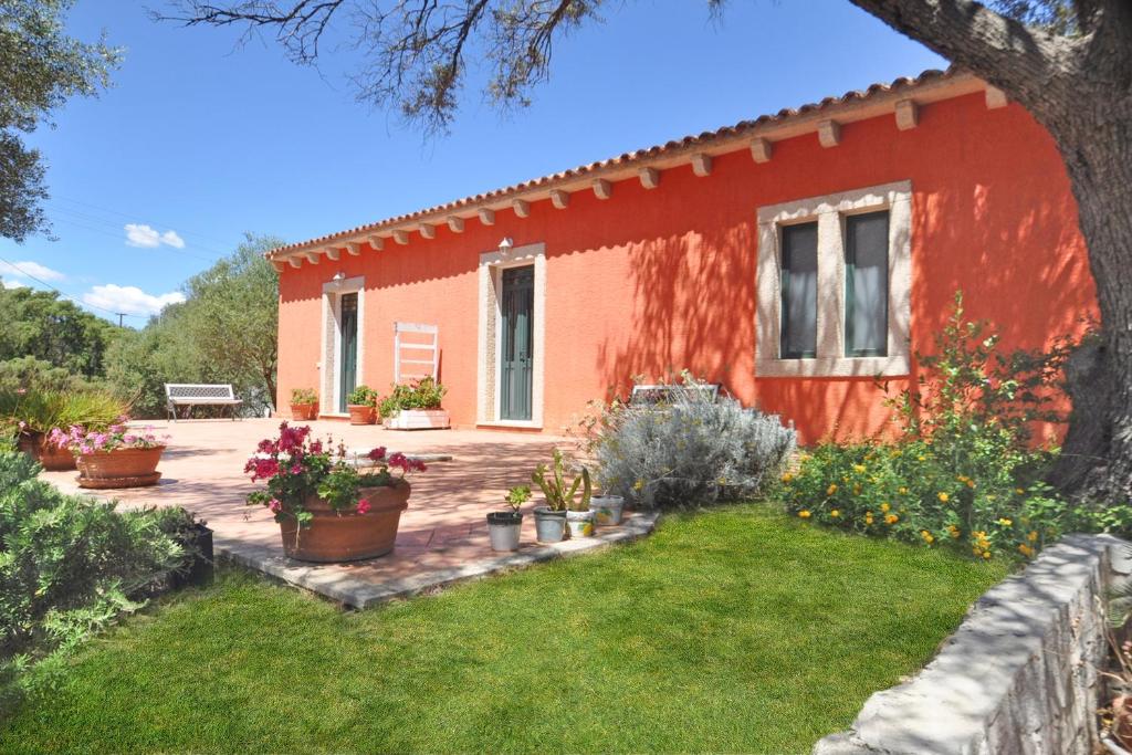 a red house with plants in a yard at Domos Pintadas -Happy Rentals in Rudalza