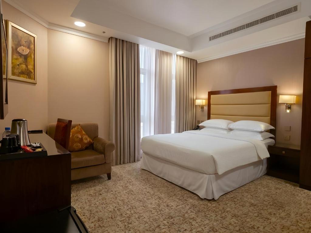 a hotel room with a bed and a chair at Grand Legacy Hotel Doha in Doha