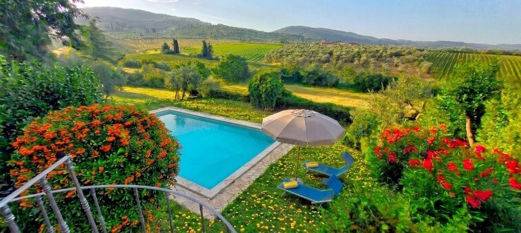 a swimming pool in a garden with flowers and an umbrella at Le Civette Country Resort with Pool in Bagno a Ripoli