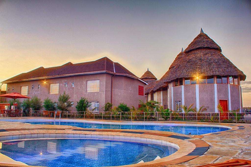 un complexe avec un grand bâtiment et une piscine dans l'établissement Comfort Gardens Sweetwaters, à Nanyuki