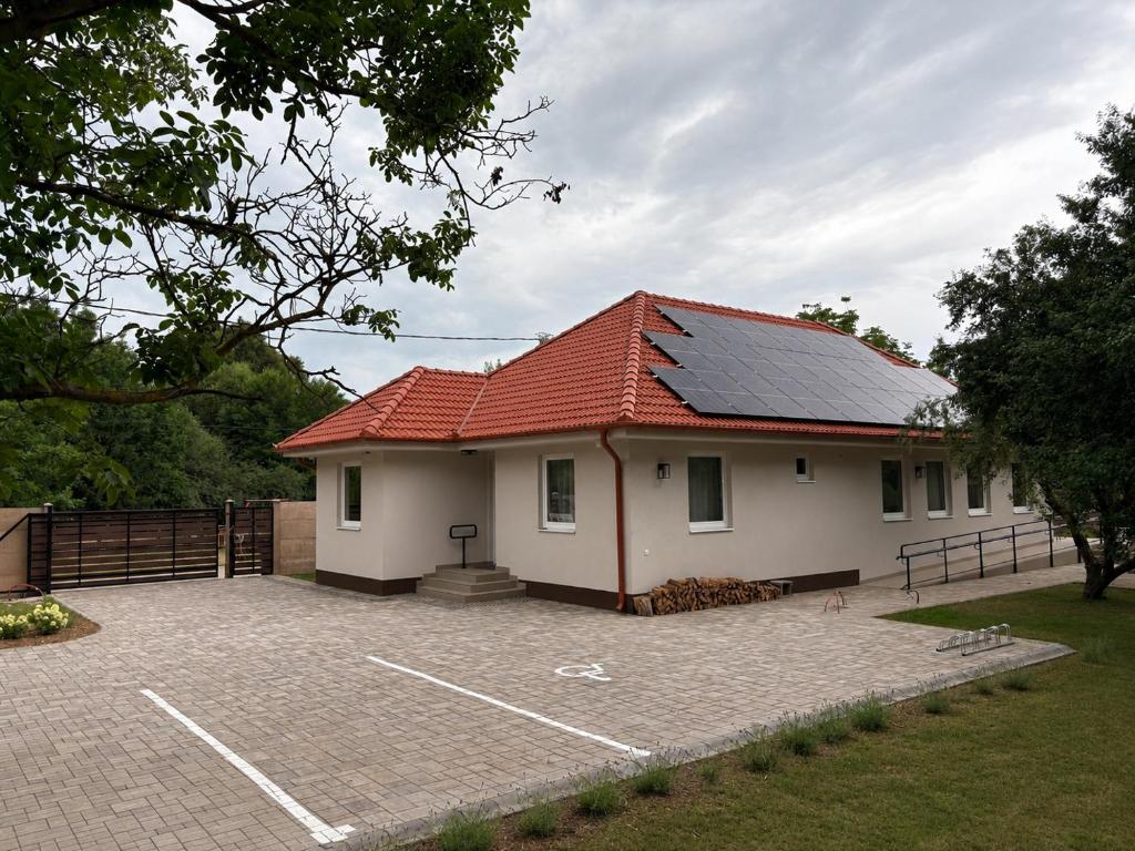a house with a red roof and a parking lot at A Napos Oldal Vendégház in Abaújkér