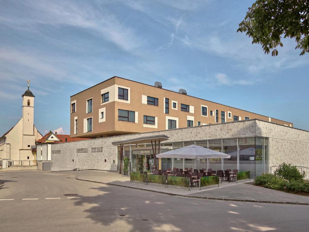 a building with tables and a building with a clock tower at Hotel Die Zeit in Sankt Veit an der Glan