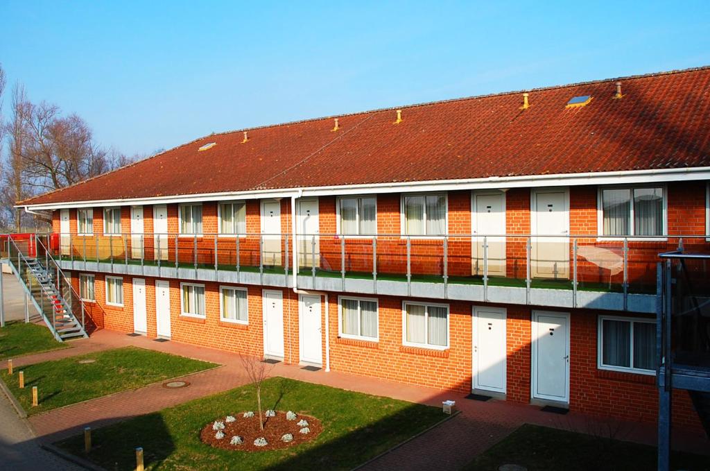 un gran edificio de ladrillo rojo con techo rojo en Hotel Ziegenkrug Rostocker Tor, en Rostock