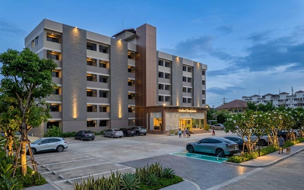 a large building with cars parked in a parking lot at Miloft Suvarnabhumi Airport Hotel in Lat Krabang