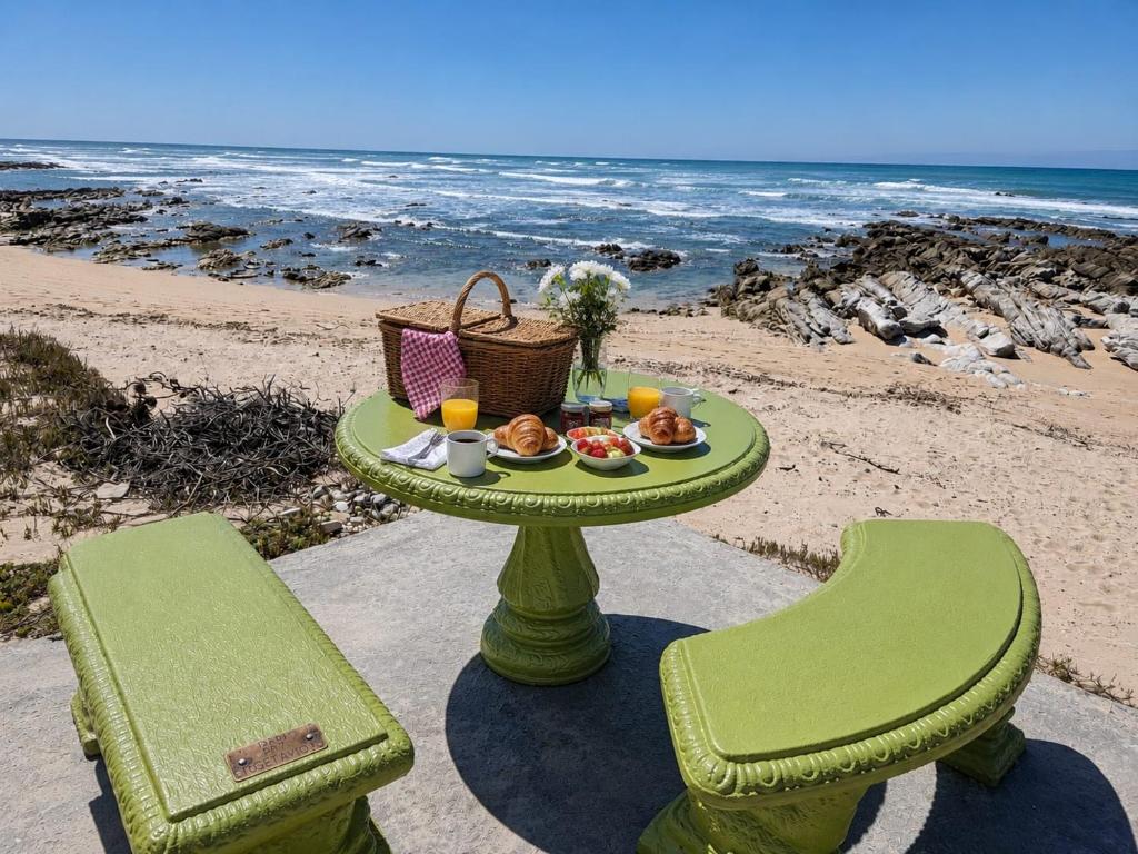 a table with a plate of food on the beach at Hello Home Struisbaai in Struisbaai