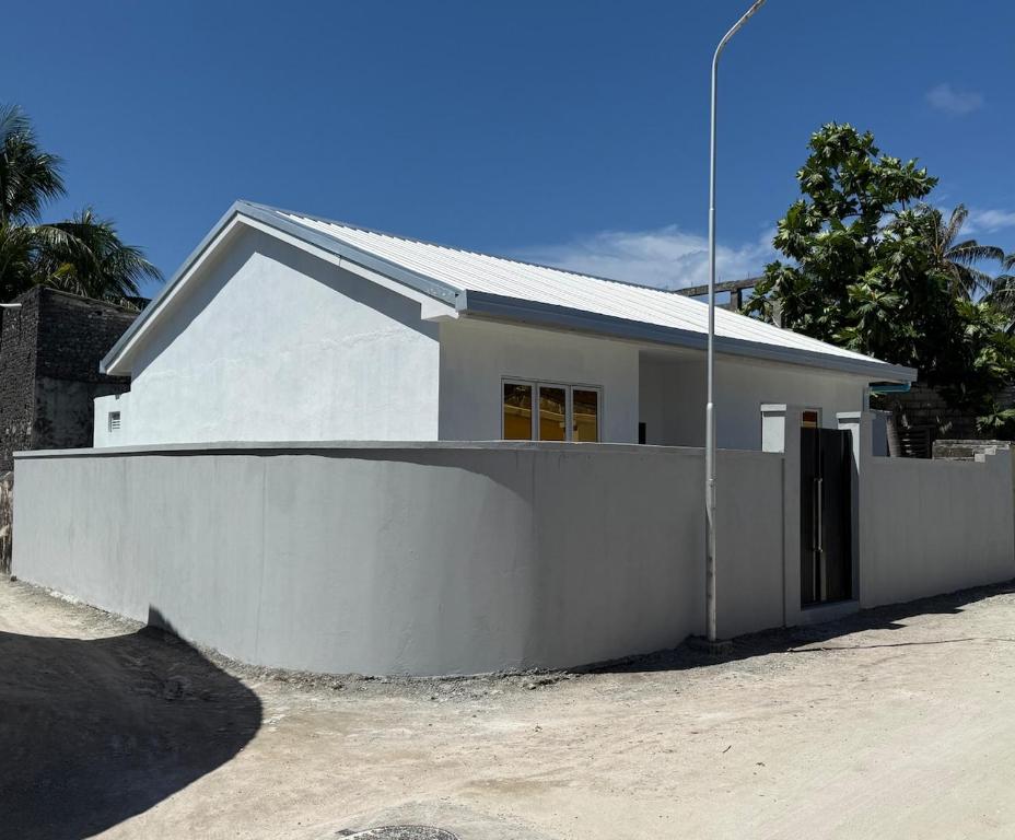 a white house with a fence in front of it at Daisy Stay Dhaandhoo in Nilandhoo