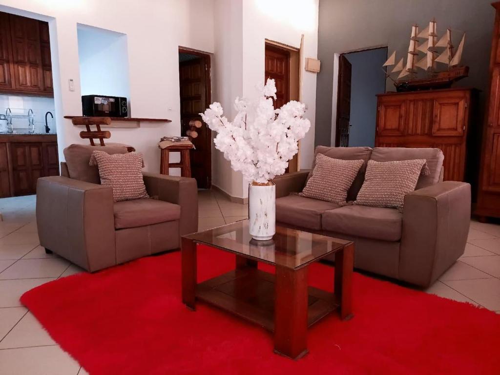 a living room with couches and a table with a vase of flowers at Appartement VIP centre ville in Toamasina