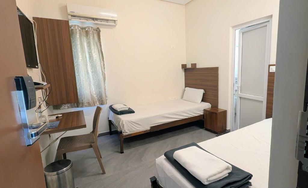 a small hospital room with a bed and a desk at Avea Accommodation in Madurai