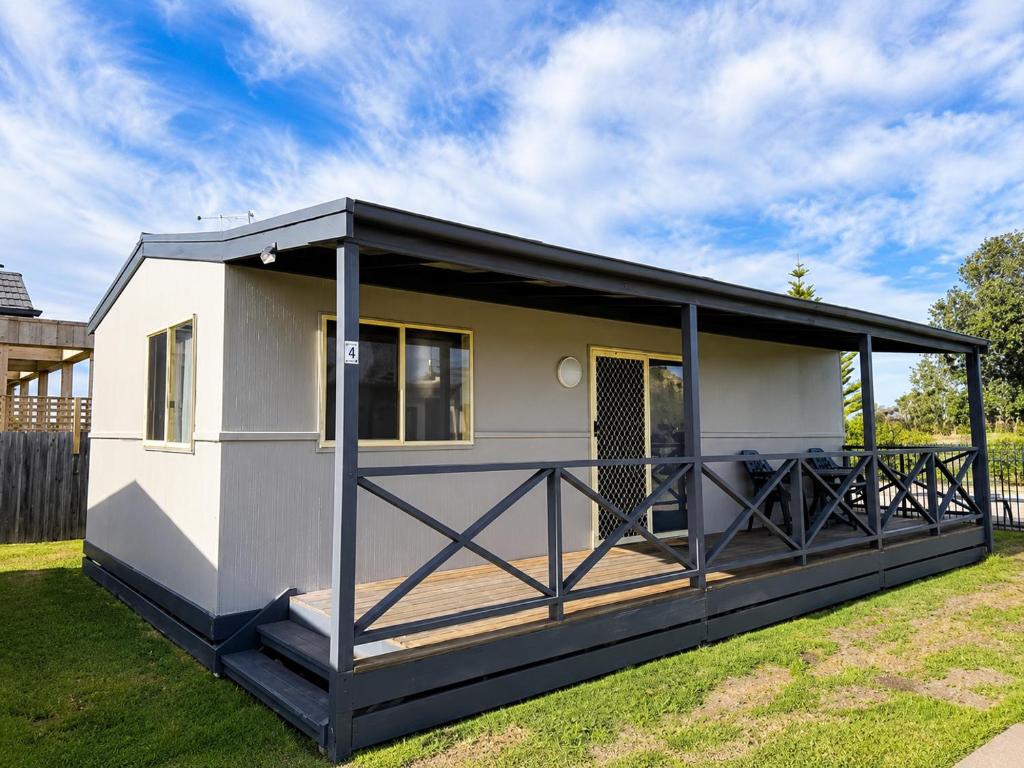 a tiny house with a deck in a yard at Waters Edge Holiday Park in Lakes Entrance