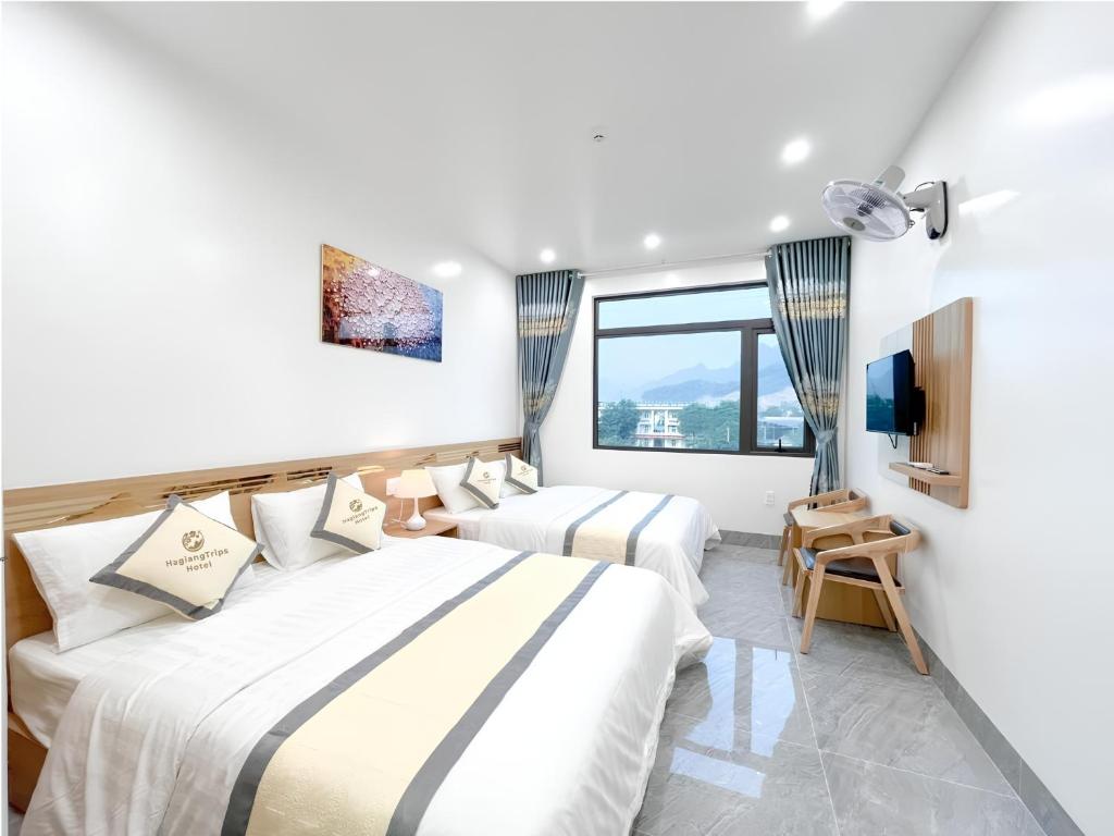a hotel room with two beds and a tv at HagiangTrips Hotel in Ha Giang