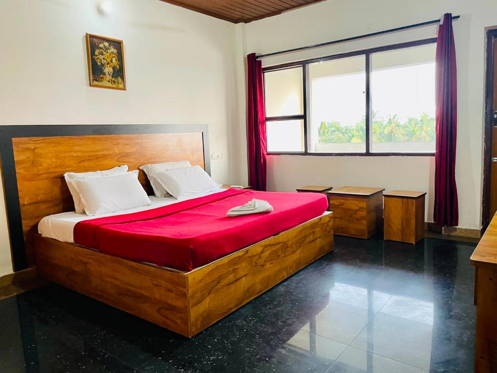 a bedroom with a large wooden bed with red sheets at Oval Retreat in Cochin