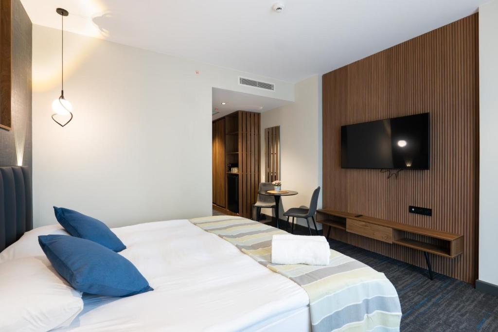 a hotel room with a bed and a tv on a wall at NOVA LUXE Hotel & Residences in Batumi