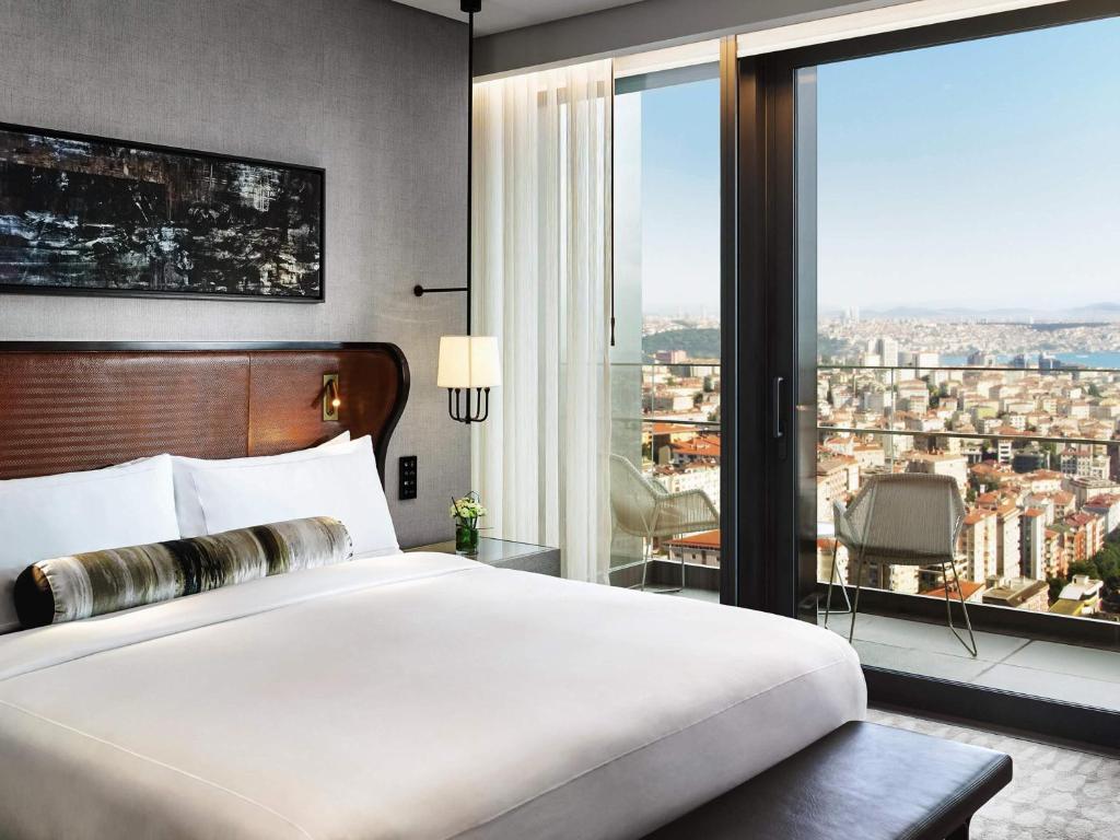 a bedroom with a large bed and a large window at Fairmont Quasar Istanbul Hotel in Istanbul