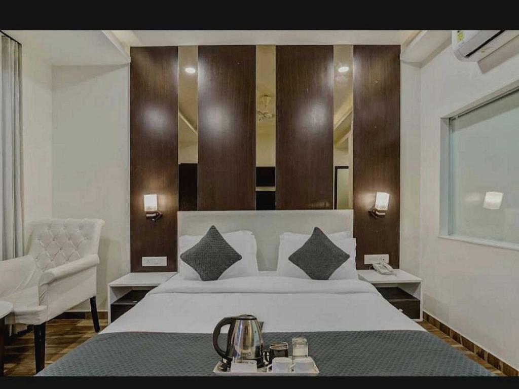 a bedroom with a large white bed and a chair at Hotel O Raas Near Peera garhi Metro Station in New Delhi