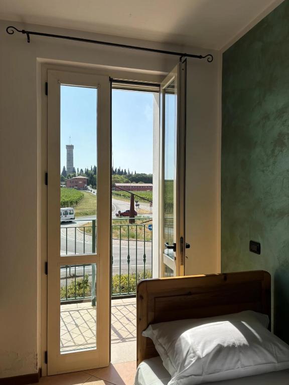 a bedroom with a bed and a door with a balcony at La Porta del Lugana - Albergo Quattro Pini in Pozzolengo