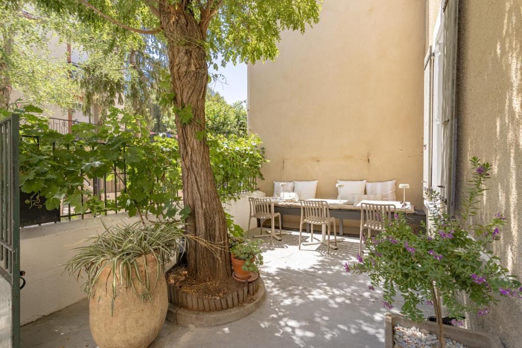 a patio with a tree and a table and chairs at L'Ecrin des Corbières in Treilles