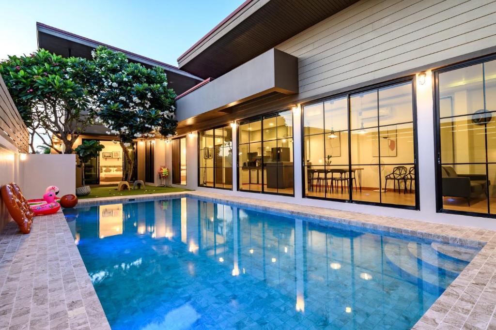 a swimming pool in front of a house at Modern Spacious 3-bed Ban Amphur Pool Villa (BA1) in Na Jomtien