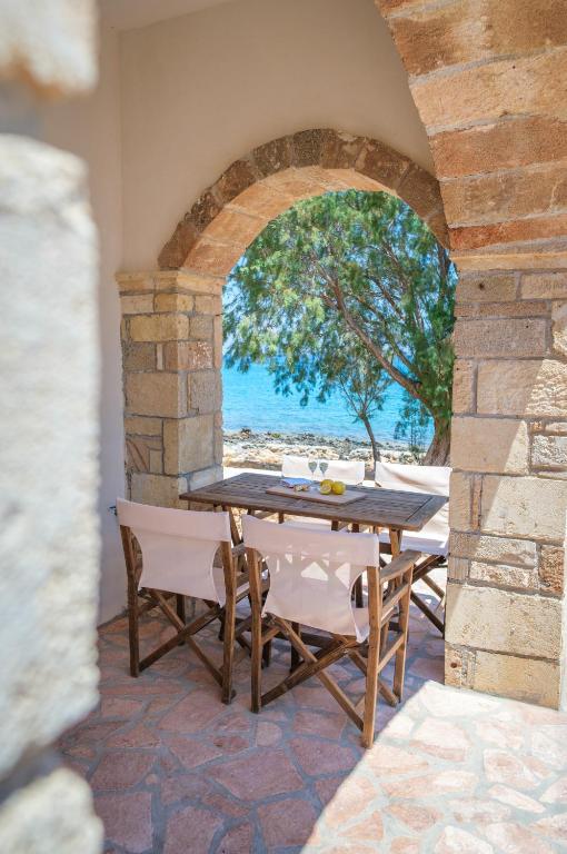 a table and chairs on a patio with a view of the ocean at The Rock Seaside House - Etheras Properties in Kythira
