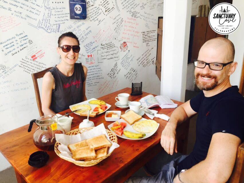 a man and woman sitting at a table with food at Sanctuary Cove Guest House in Polonnaruwa