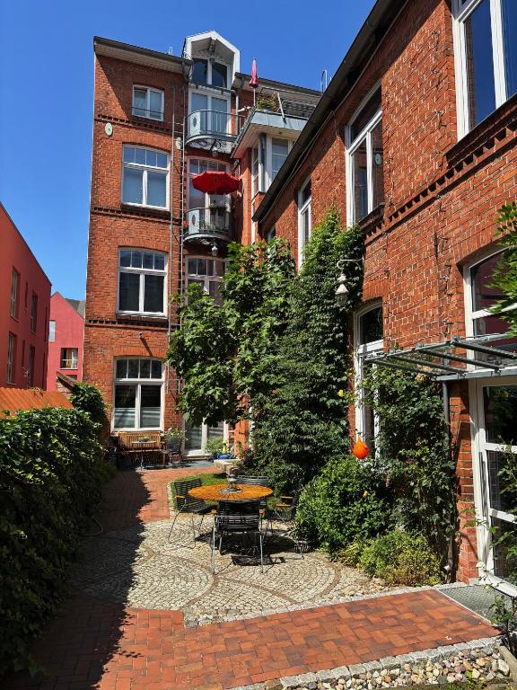 a courtyard of a brick building with a table and chairs at Dat Kleenood in Wismar