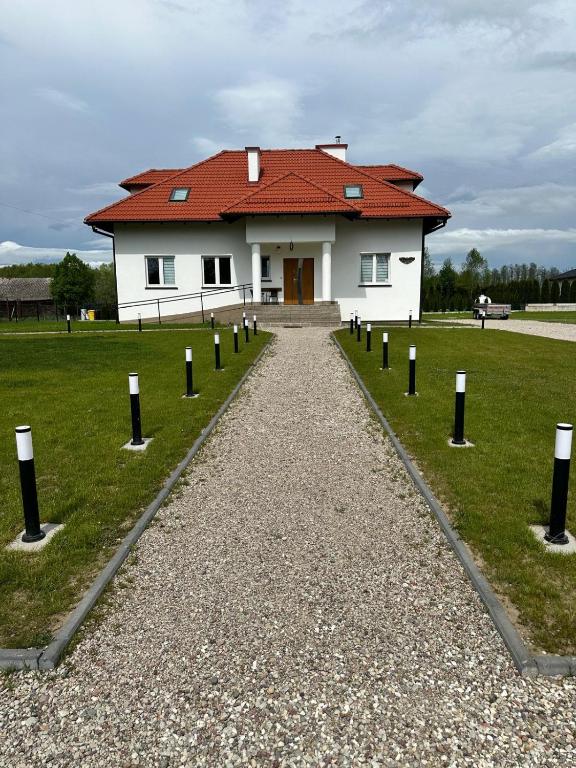a house with a red roof and a gravel road at Noclegi Antoniewo in Morąg