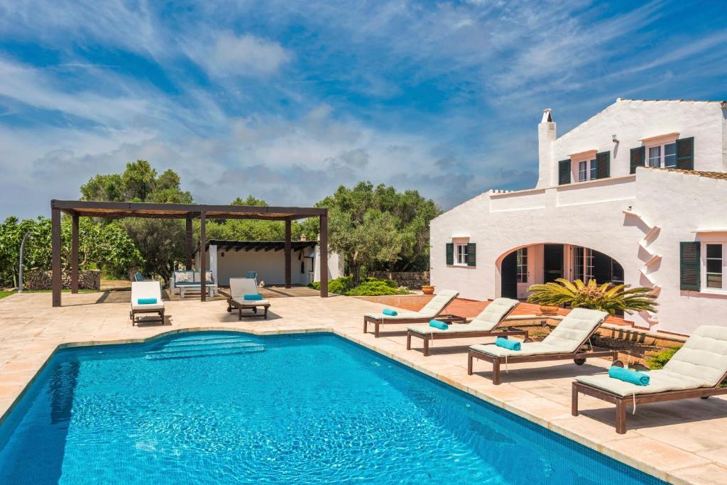 a swimming pool with lounge chairs and a house at Villa Mig Coster - Refugio rural en finca privada in Sant Lluis