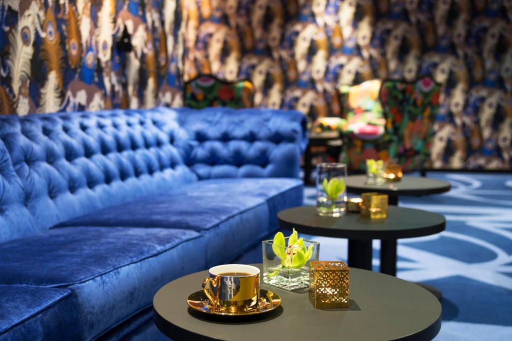 a living room with a blue couch and two tables at Thon Hotel Terminus in Oslo