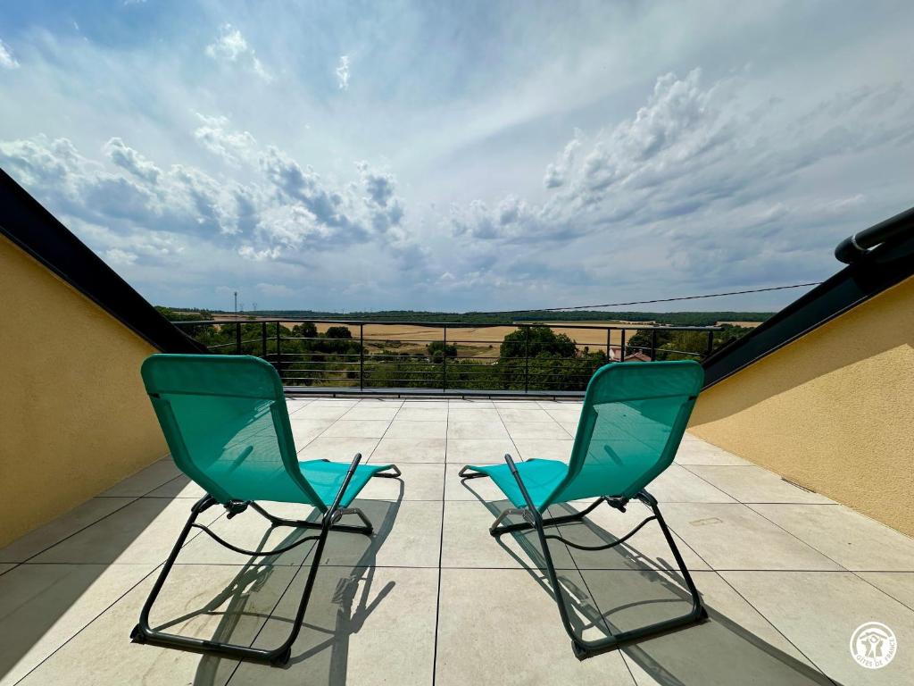 two green chairs sitting on a balcony with a view at Le Creux Percé in Pasques