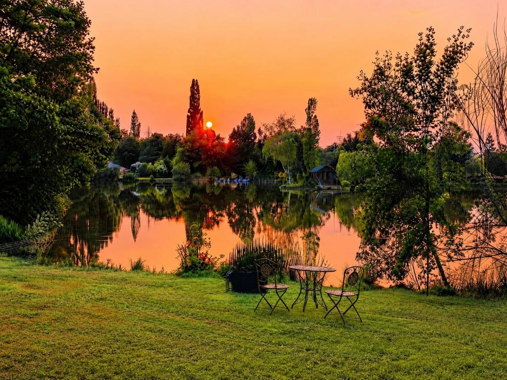 a sunset over a lake with a table and chairs at Au Lit D'Ô in Bressuire
