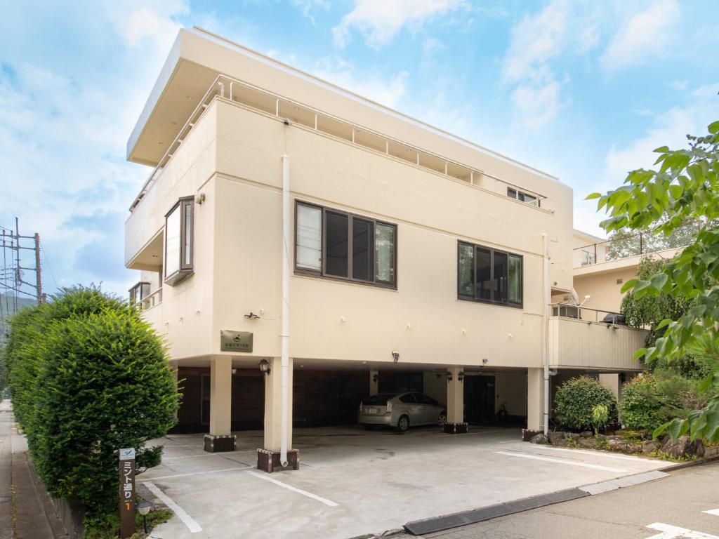 a white building with a car parked in a parking lot at Beni Fujien in Yamanakako