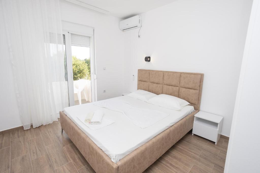 a white bedroom with a large bed and a window at Babulje in Ulcinj