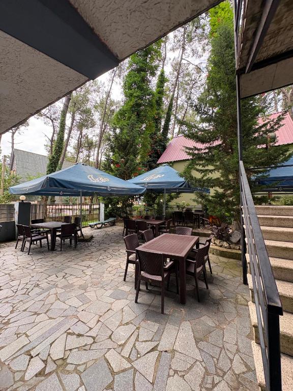 a patio with tables and chairs and blue umbrellas at hotel shomari in Grigoleti