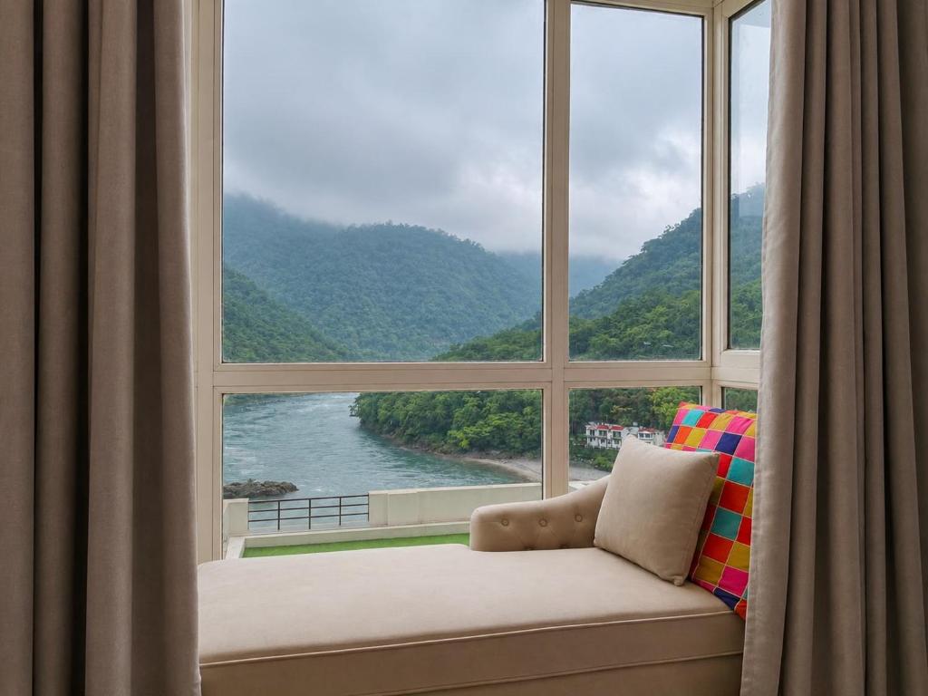 a couch sitting in front of a large window at Aloha Serenity By Evara -Ganga View Stays in Rishīkesh