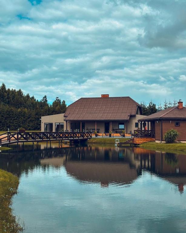 a building with a bridge over a body of water at Sodyba "Bičiuliai" in Plungė