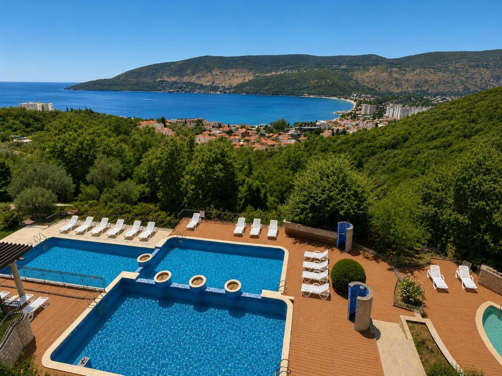 an overhead view of two swimming pools and chairs and the ocean at Adriatic Monte Apartments in Tušupi