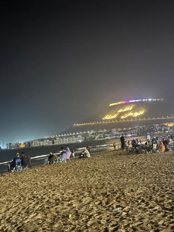 a group of people sitting on the beach at night at Villa adi in Essaouira