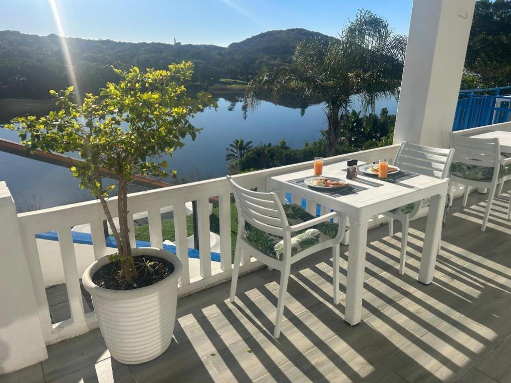 a white table and chairs on a balcony with a tree at Blues at Bonza Bay Beach in Beacon Bay