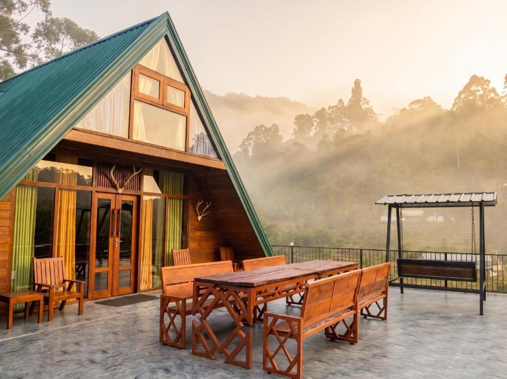 a house with a table and benches on a balcony at Top Mountain Resort in Diyatalawa