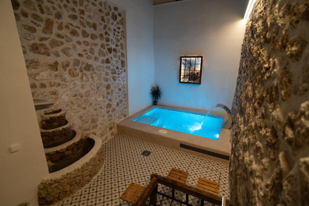 a bathroom with a swimming pool with a stone wall at Casa de Mamachon in Cazorla