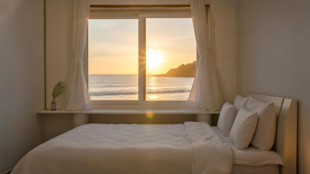 a bedroom with a bed and a window with the ocean at Goseong Jajackdo Aroma Pension in Goseong