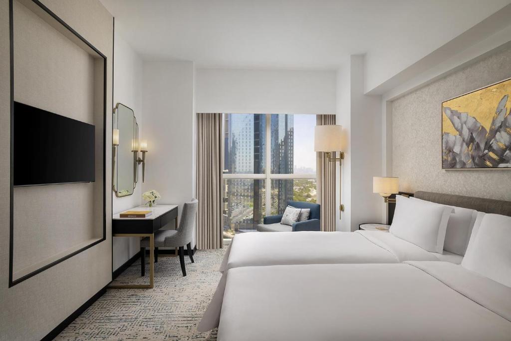 a hotel room with two beds and a desk at Dusit Thani Dubai in Dubai