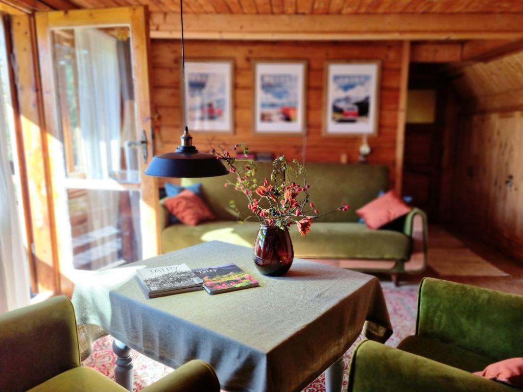 a living room with a table with a vase of flowers on it at Miodowa Chata in Łapsze Niżne