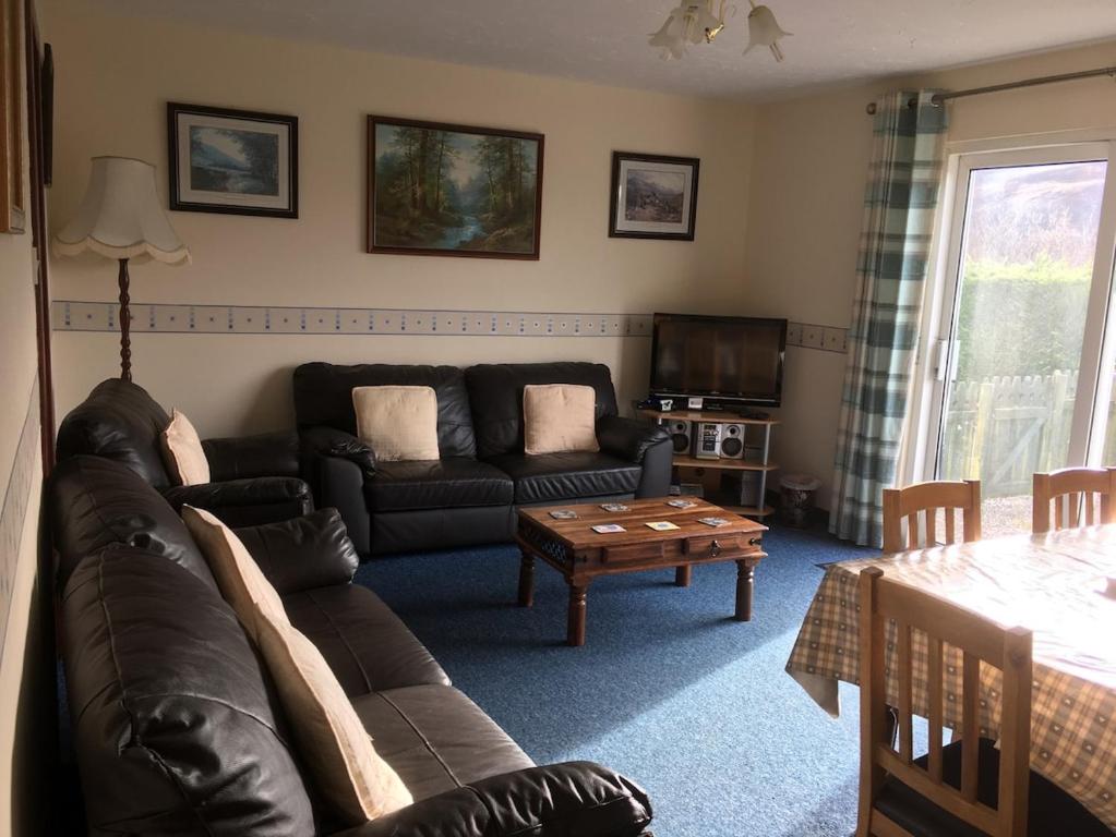 a living room with a couch and a table at Buzzards Nest Cottage in Roybridge