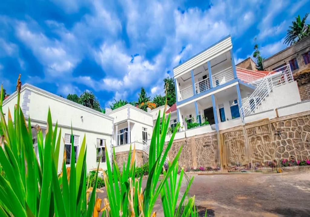 a white house with green plants in front of it at Choice Lounge in Rubavu